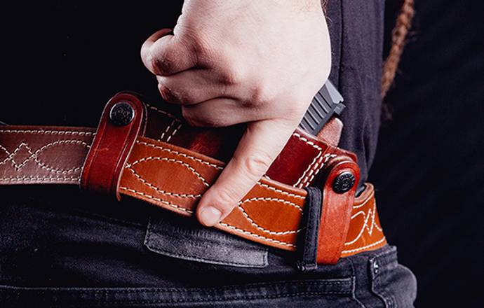 A guy with an inside the waistband SIG Sauer P226 holster made of mahogany leather, drawing gun