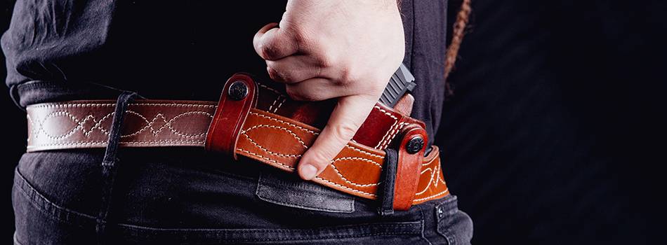 A guy with an inside the waistband SIG Sauer P226 holster made of mahogany leather, drawing gun