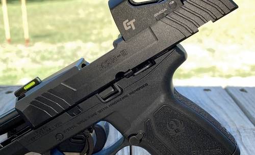 A Ruger Max 9 semi auto pistol with a red dot sight installed to its slide and a racked slide