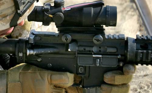 A soldier with an AR-15 rifle aiming through his rifle scope