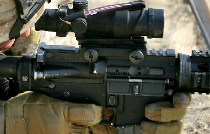 A soldier with an AR-15 rifle aiming through his rifle scope