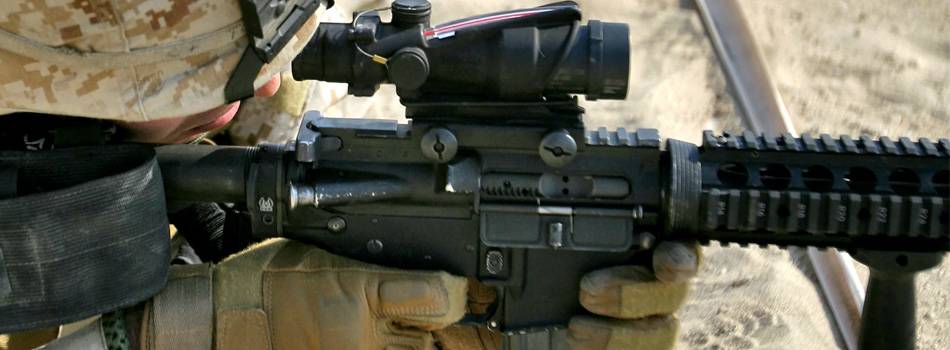 A soldier with an AR-15 rifle aiming through his rifle scope