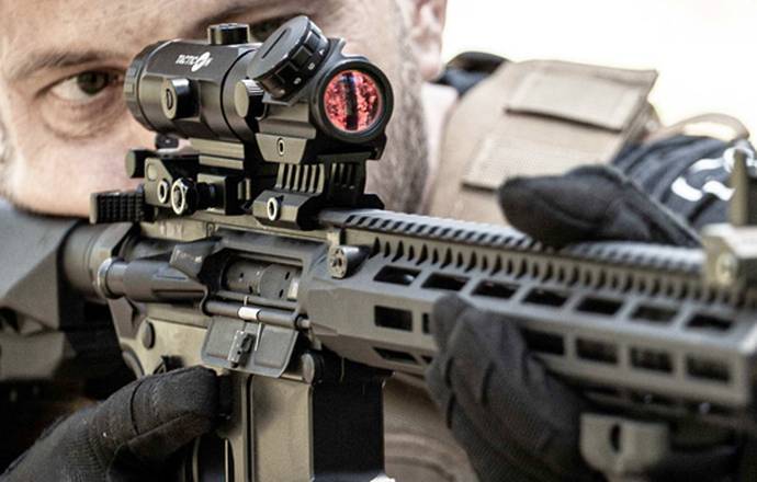 A soldier aiming through his AR-15 rifle red dot sight