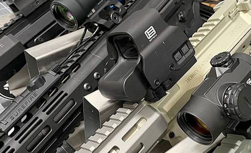 A set of AR-15 rifles, each featuring a red dot sight or scope