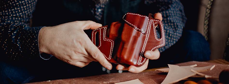 A craftsman showcasing a beautiful mahogany leather holster he's just finished.