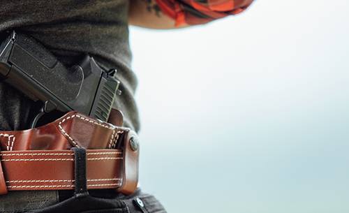A guy with a custom inside the waistband leather holster, with his shirt up, the gun and holster are partially visible