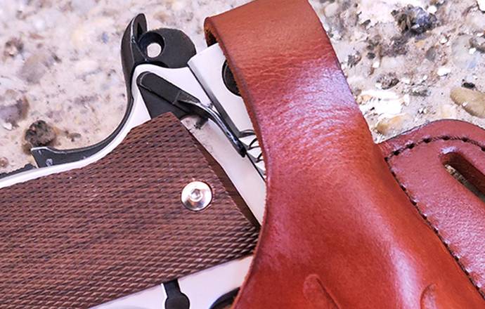 A 1911 smith & wesson pistol in cocked and locked condition in a mahogany leather holster