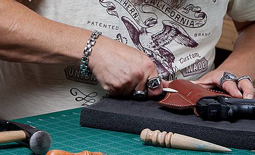 a craftsman molding a leather holster on a handgun replica