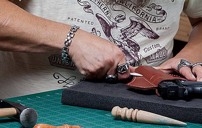 a craftsman molding a leather holster on a handgun replica