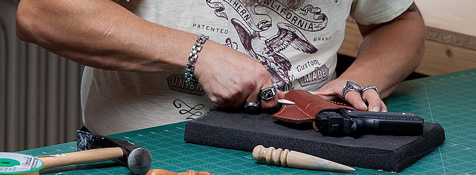 a craftsman molding a leather holster on a handgun replica