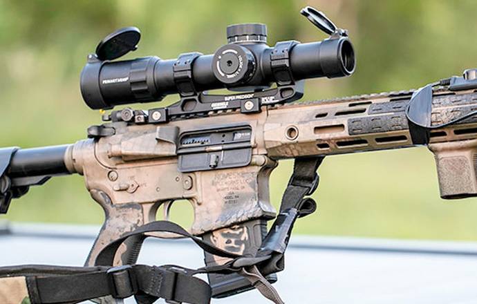 An AR-15 rifle in camo coating with a rifle scope attached to its top