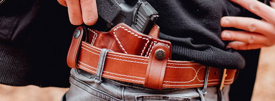 A guy with an inside the waistband Taurus g3c holster made of mahogany leather, drawing gun