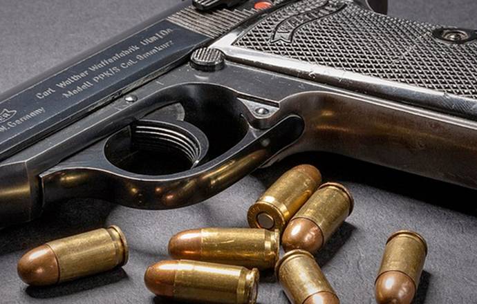 Walther PPK pistol on a desk with bullets dispersed around it