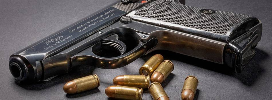 Walther PPK pistol on a desk with bullets dispersed around it