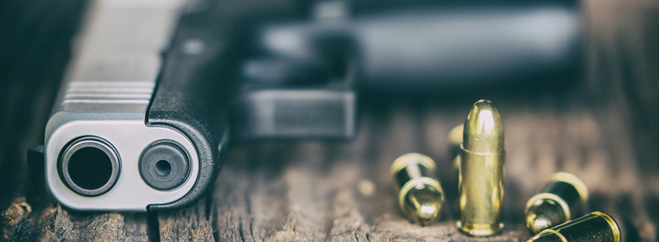 Glock 43x Review - Glock 43x pistol lying on a table, front view, there's bullet scattered around the pistol