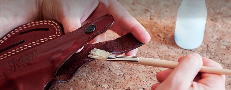 HAnds applying liquid on a leather holster with a brush