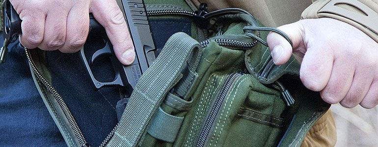 Close up on a person drawing a firearm from his concealed carry bag