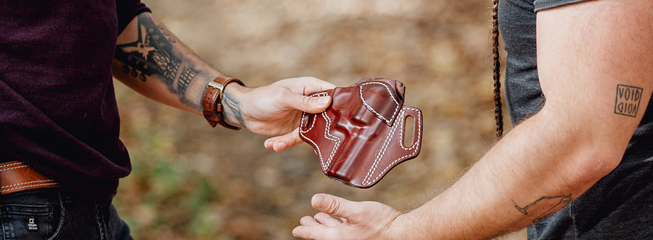 a guy passing another one a leather j frame revolver holster