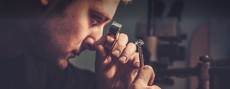 A man with a magnifying glass examines a diamond