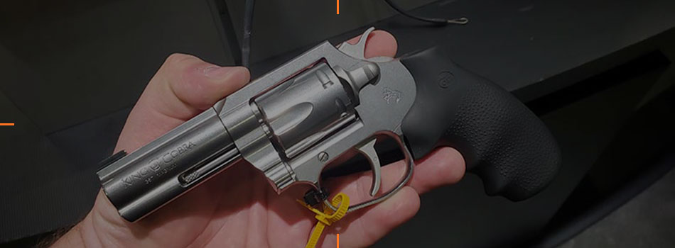 Colt King Cobra stainless steel revolver with black grip held in a hand.