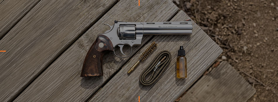 Colt Python revolver with cleaning kit and accessories on a wooden outdoor table.