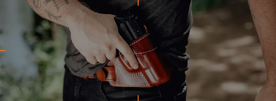 Man drawing a handgun from a brown leather cross draw holster worn at the waist.