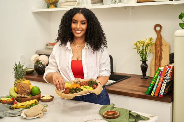 Eden Hagos in a kitchen holding a plate of food