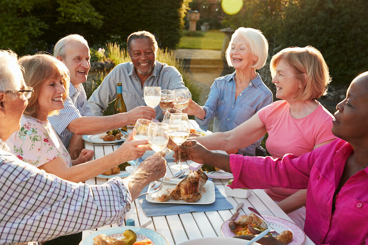 Group of senior friends toasting at dinner enjoying the benefits of senior living.