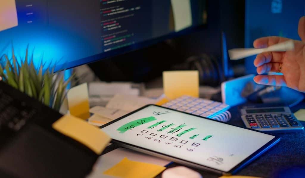 A developer working at a desk with multiple screens showing code and tasks.