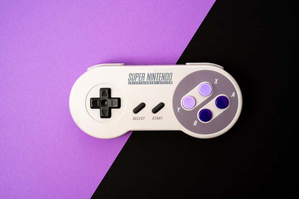 A Super Nintendo controller lying on a split purple-and-black background.