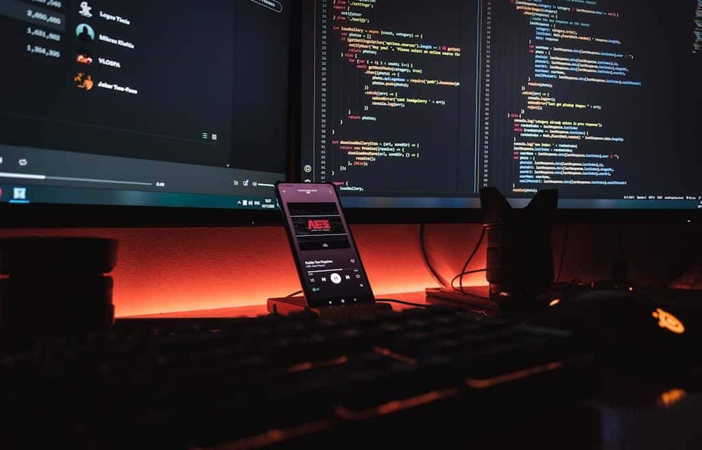 Code on dual monitors under warm ambient light, a workstation set up for hands-on programming.