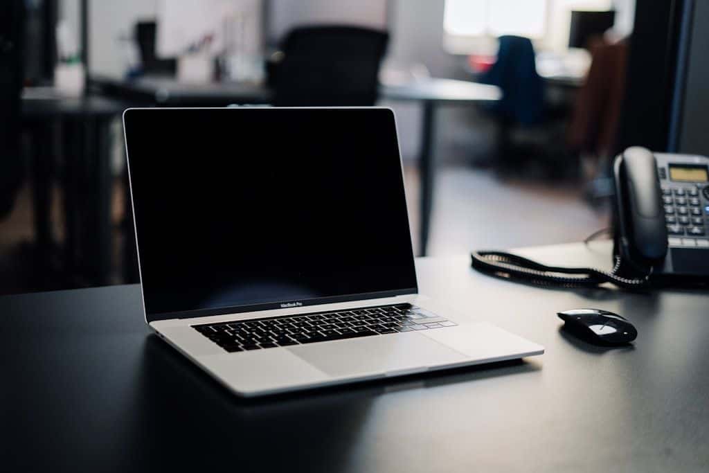 A MacBook Pro on a dark office desk.