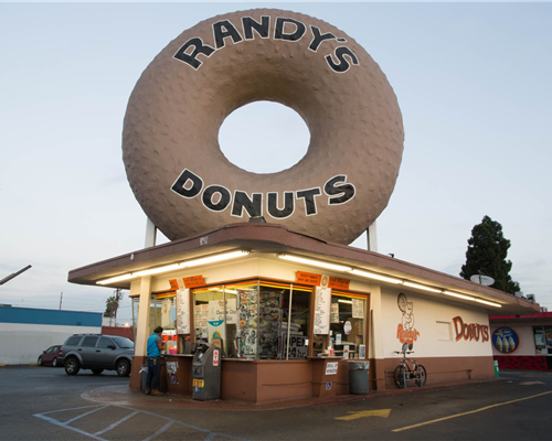 The site is a typical mid-century drive-up restaurant with a giant donut on its roof