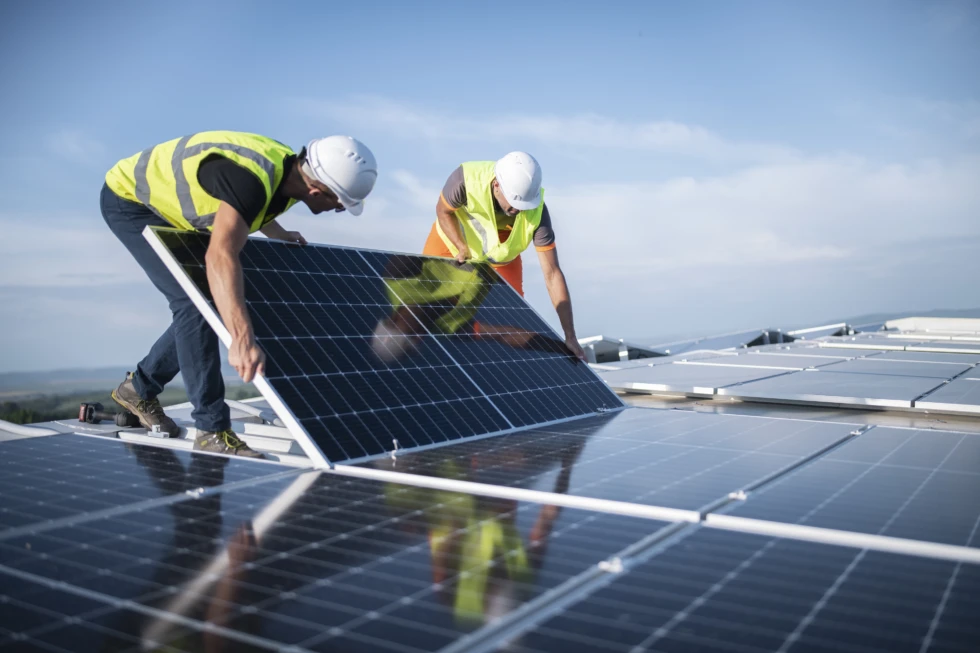 Two engineers installing solar panels on roof