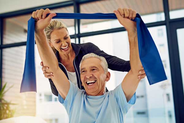 A senior man exercising with workout bands with the help of a physical therapist.