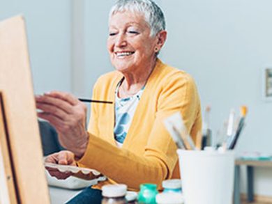 a senior woman paints in a brightly lit studio