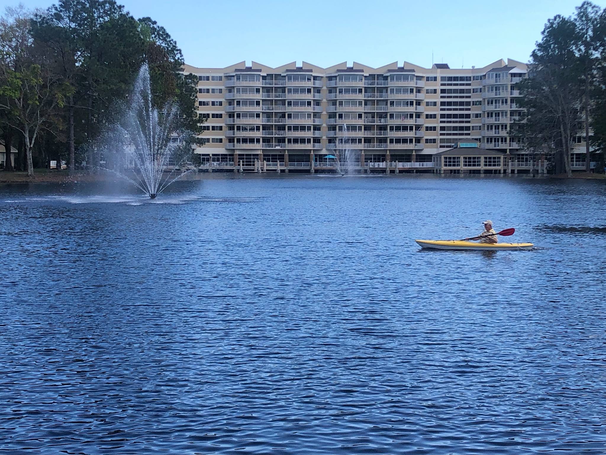 A senior man kayaks in the lake alongside Cypress Village senior living community