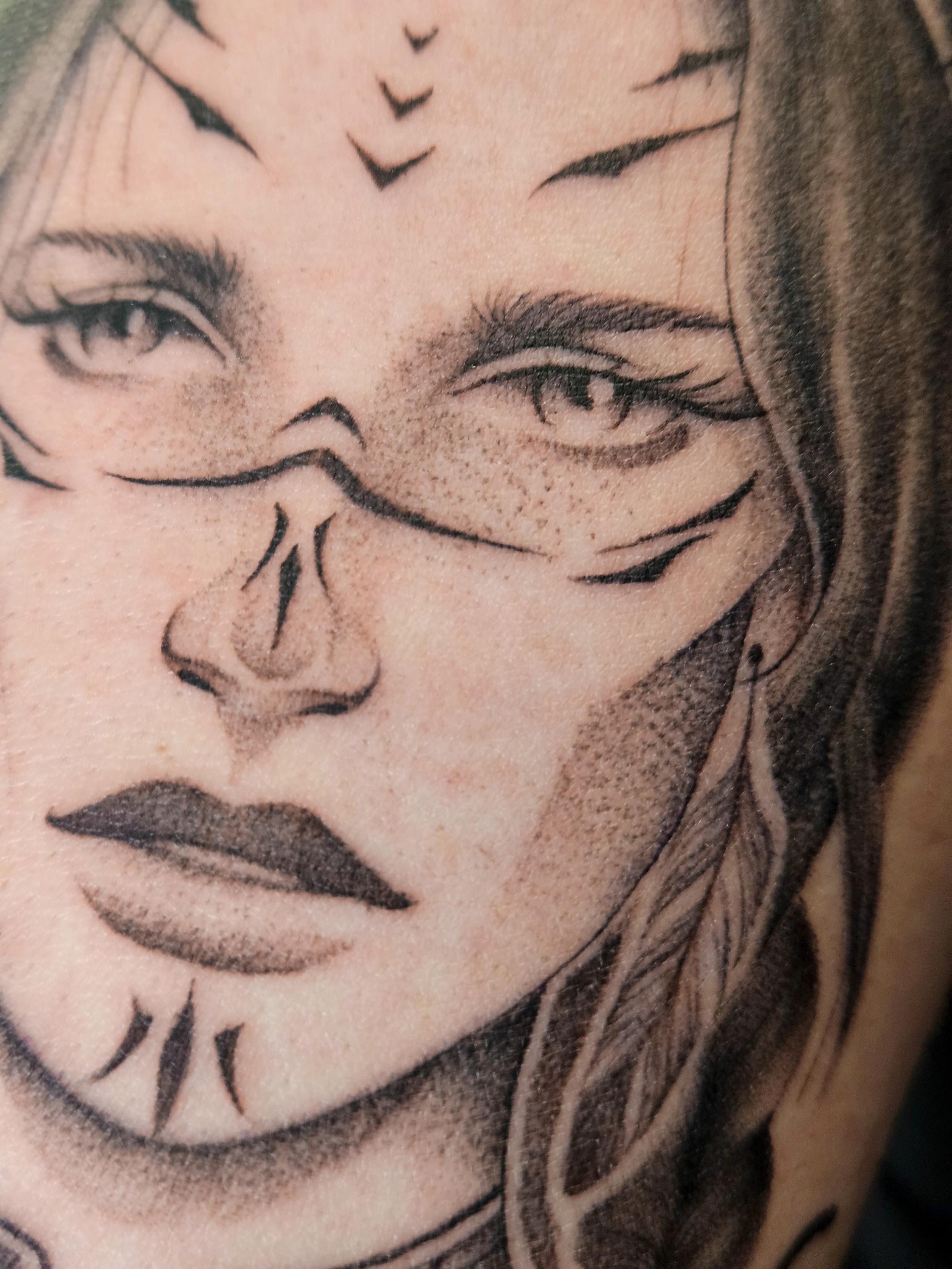 Ce tatouage présente un portrait réaliste en noir et gris d'une femme aux traits délicats et expressifs. Le visage est orné…