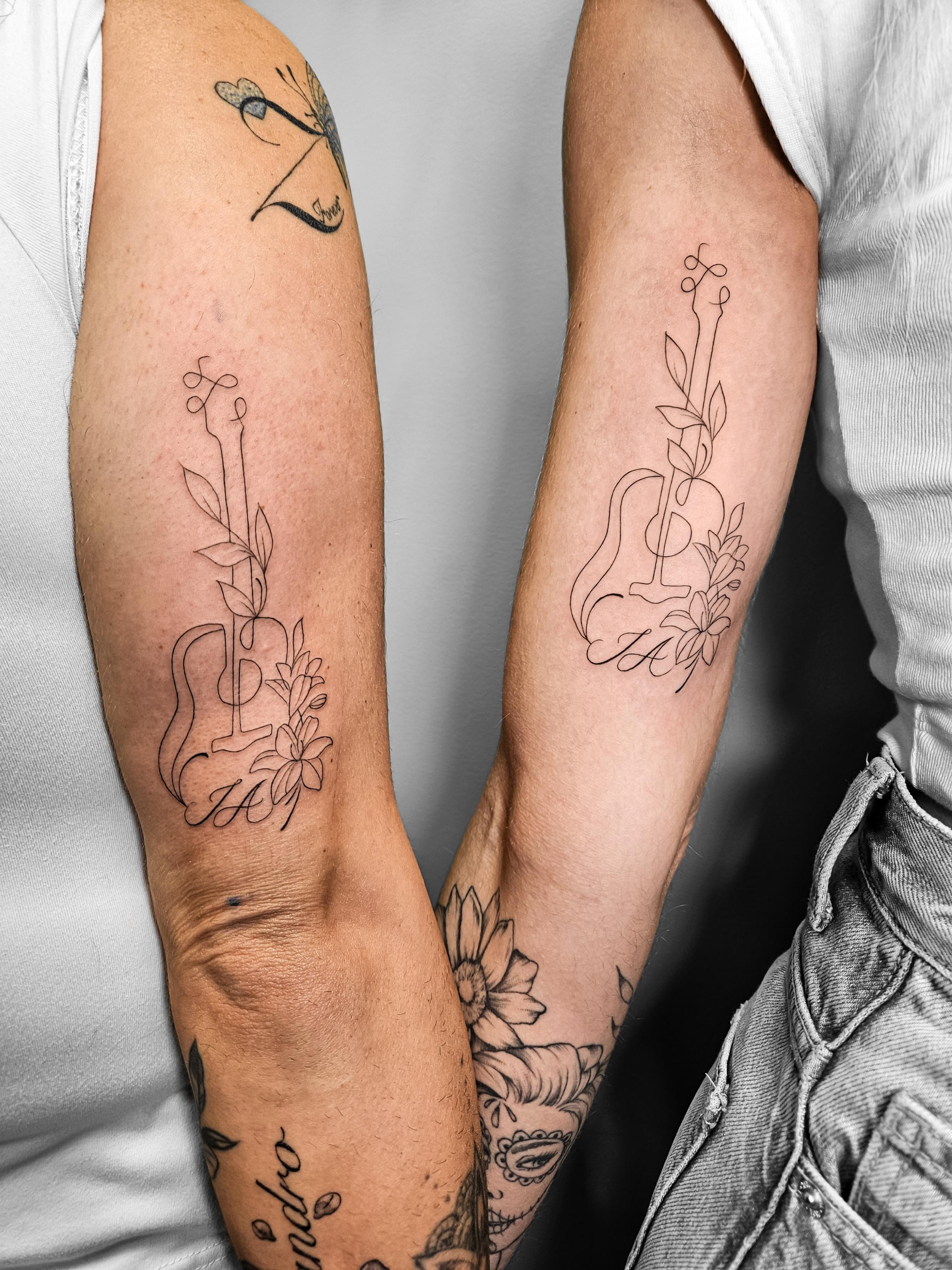 Ce tatouage présente un style fine-line délicat avec des motifs floraux identiques sur les deux avant-bras. Chaque tatouage…