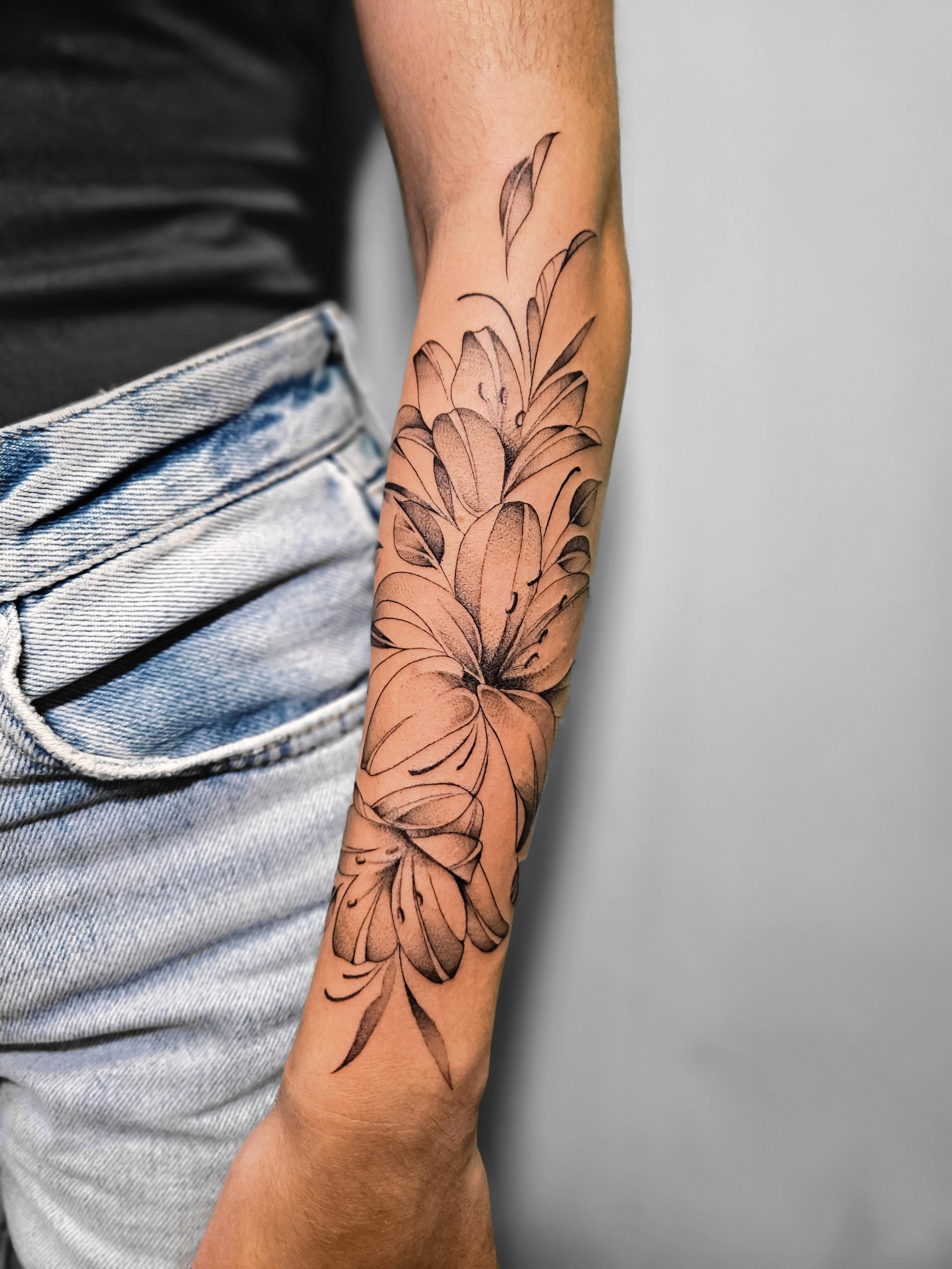 Ce tatouage présente un magnifique bouquet de lys réalisé dans un style fine-line élégant et délicat. L'œuvre s'étend sur la…