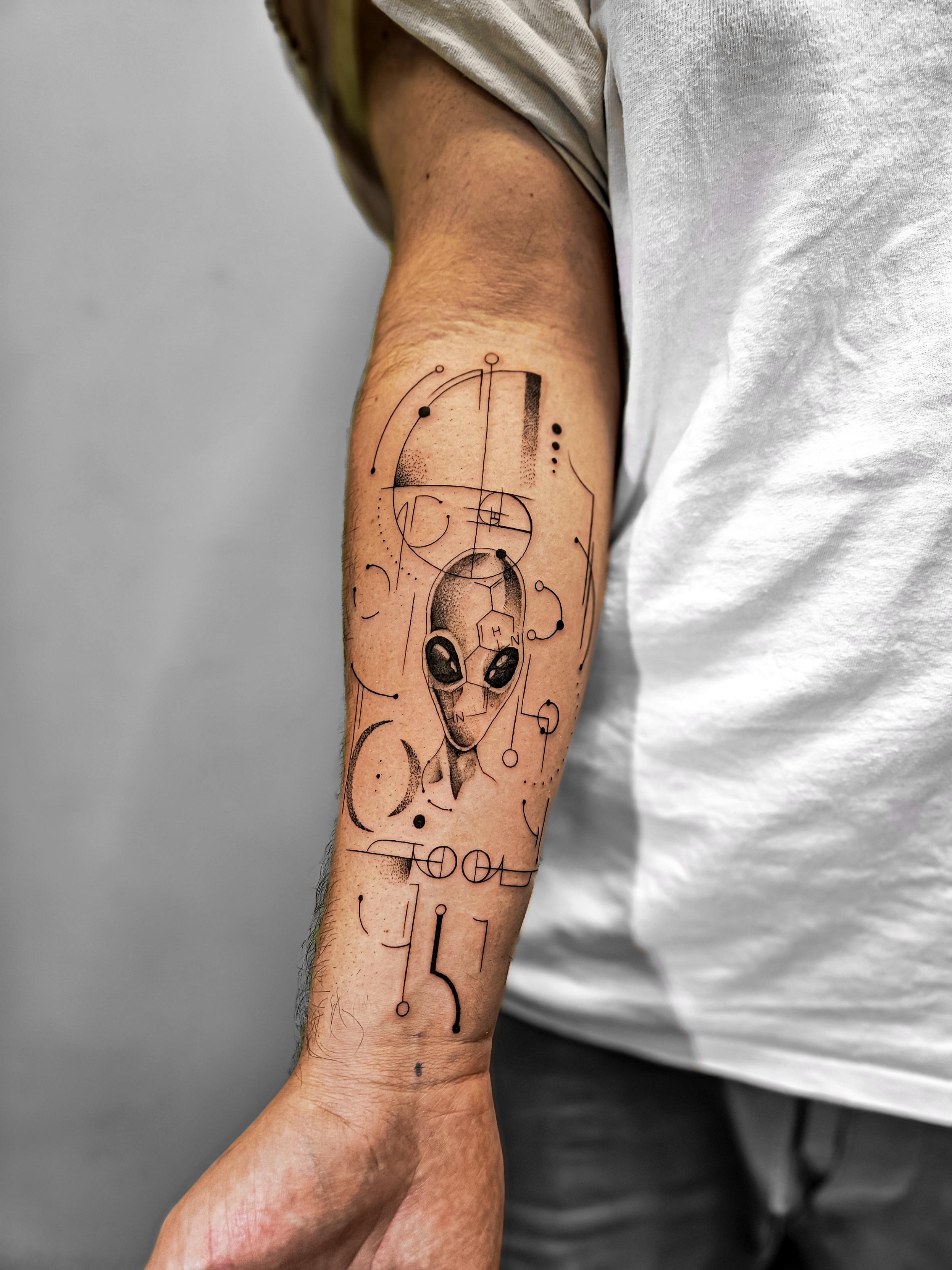Ce tatouage présente un design complexe et artistique dans un style fine-line et géométrique, situé sur l'avant-bras.…