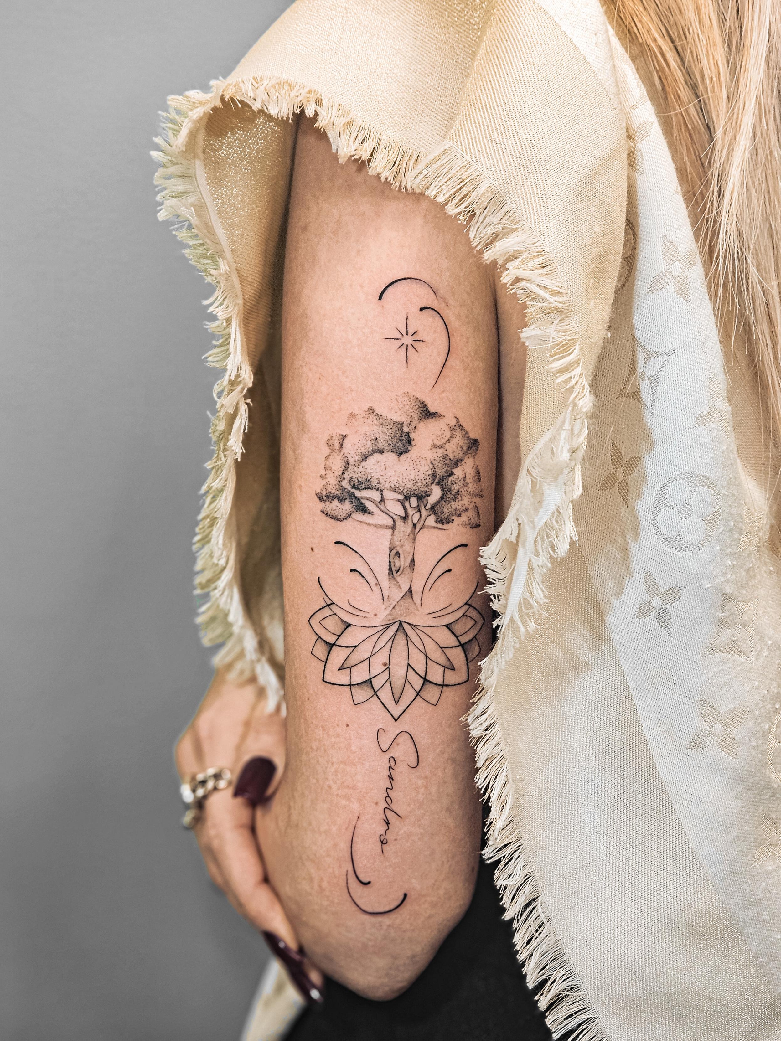 Ce tatouage délicat à l'encre noire présente une composition verticale élégante sur l'avant-bras. L'élément central est un…