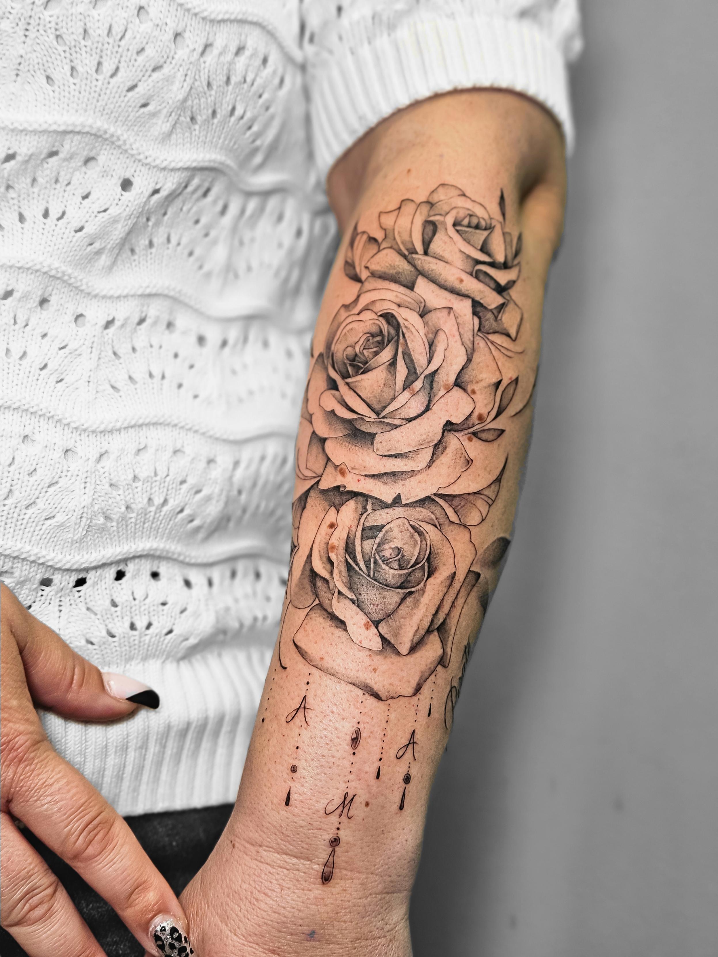 Ce tatouage floral présente trois roses réalistes disposées verticalement le long de l'avant-bras. Les roses sont exécutées…