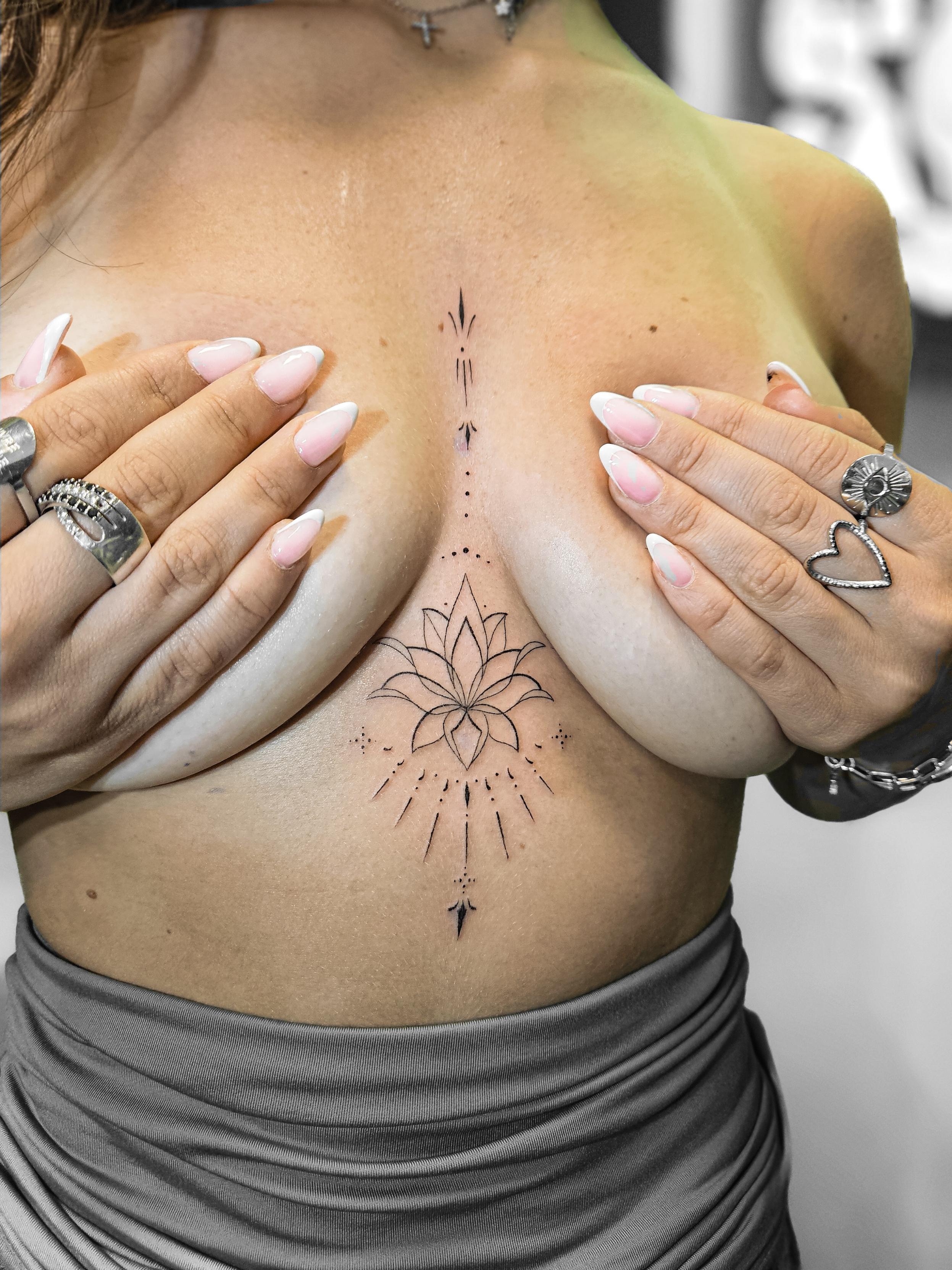 Ce tatouage présente un design géométrique et ornemental centré sur le sternum et s'étendant verticalement sur le torse.…