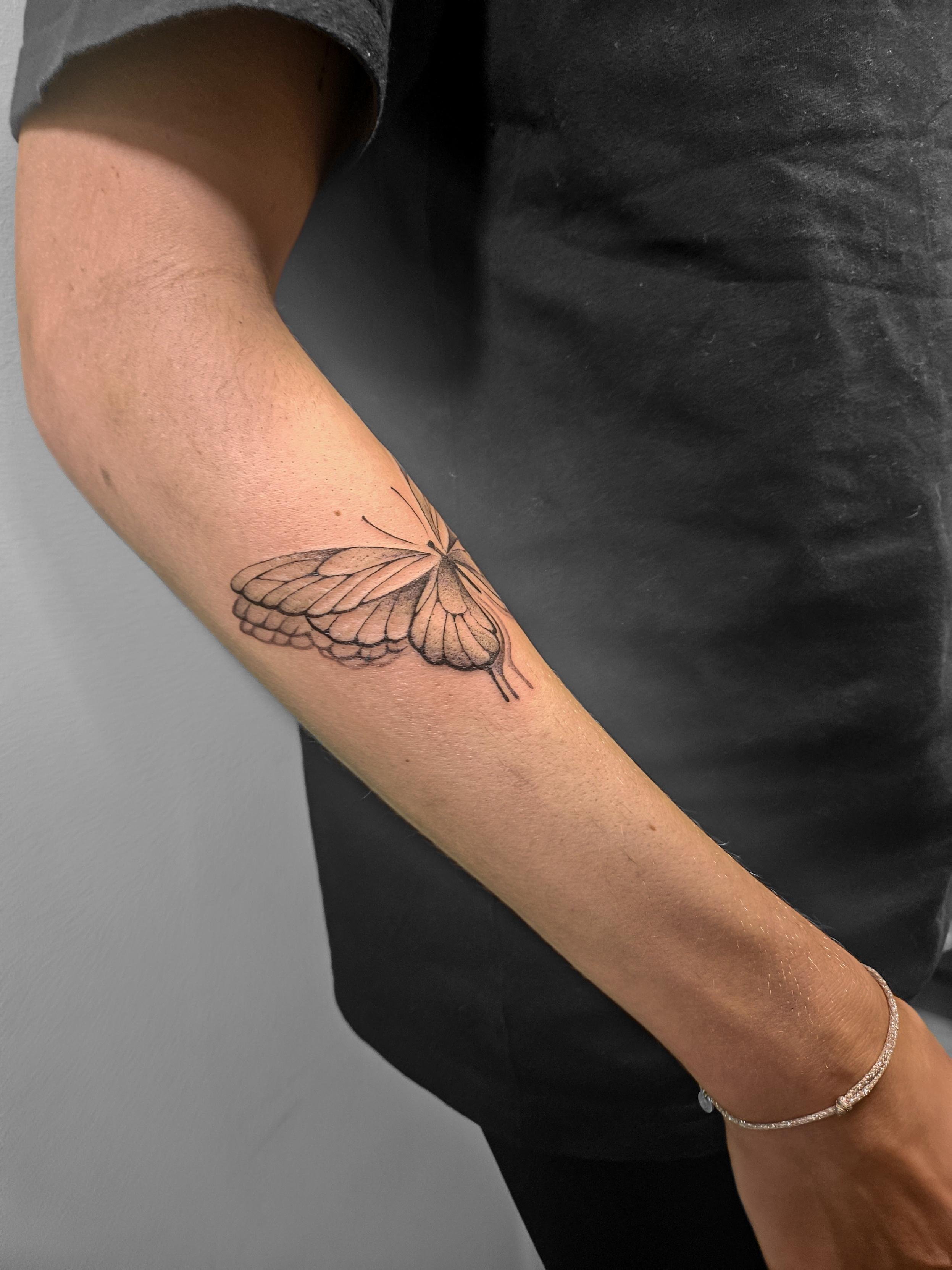 Ce tatouage représente un papillon élégant réalisé dans un style fine-line délicat et précis. Le papillon est tatoué sur…