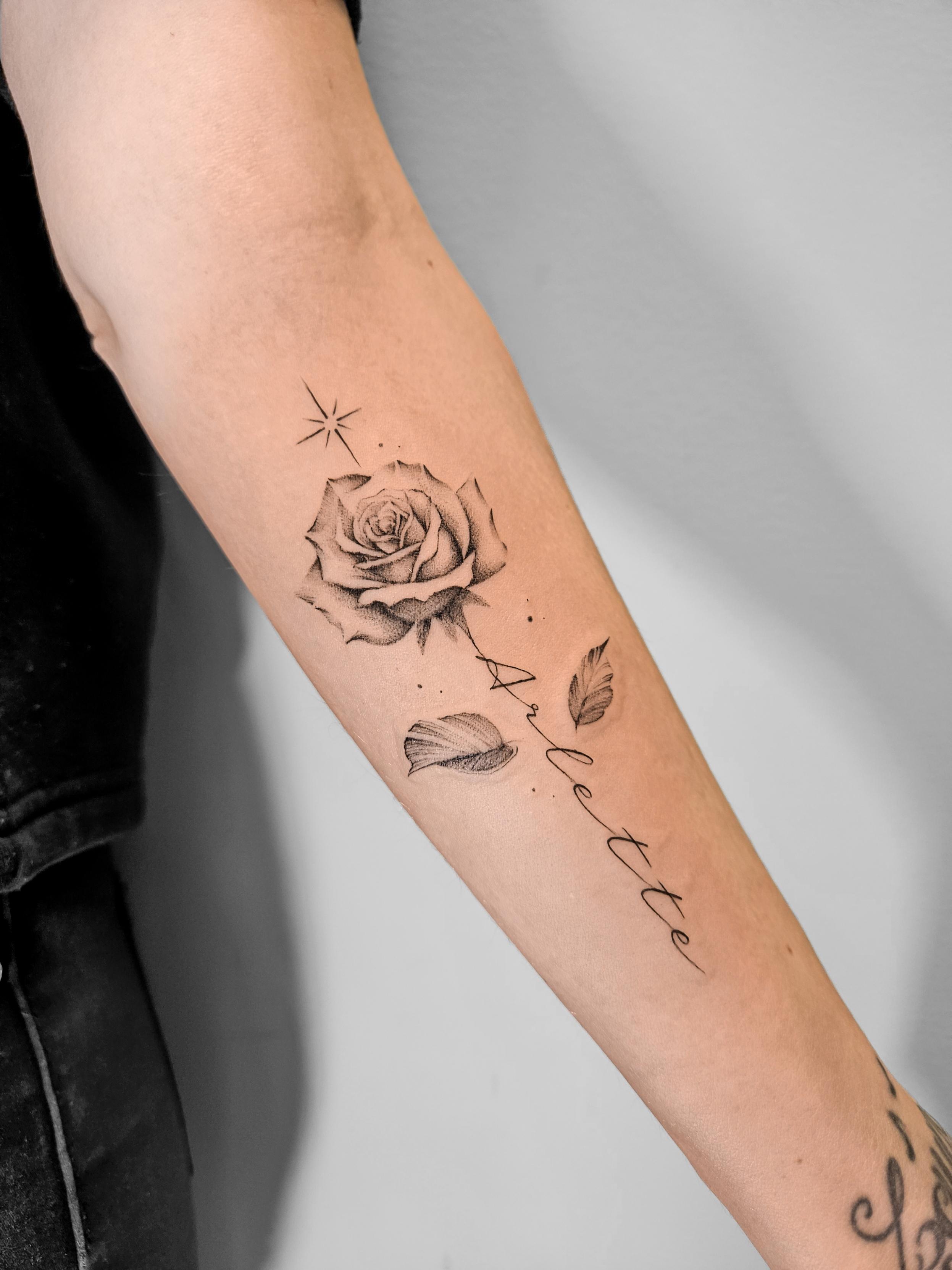 Ce tatouage délicat en fine-line présente une rose détaillée comme élément central, réalisée avec des ombrages subtils et un…