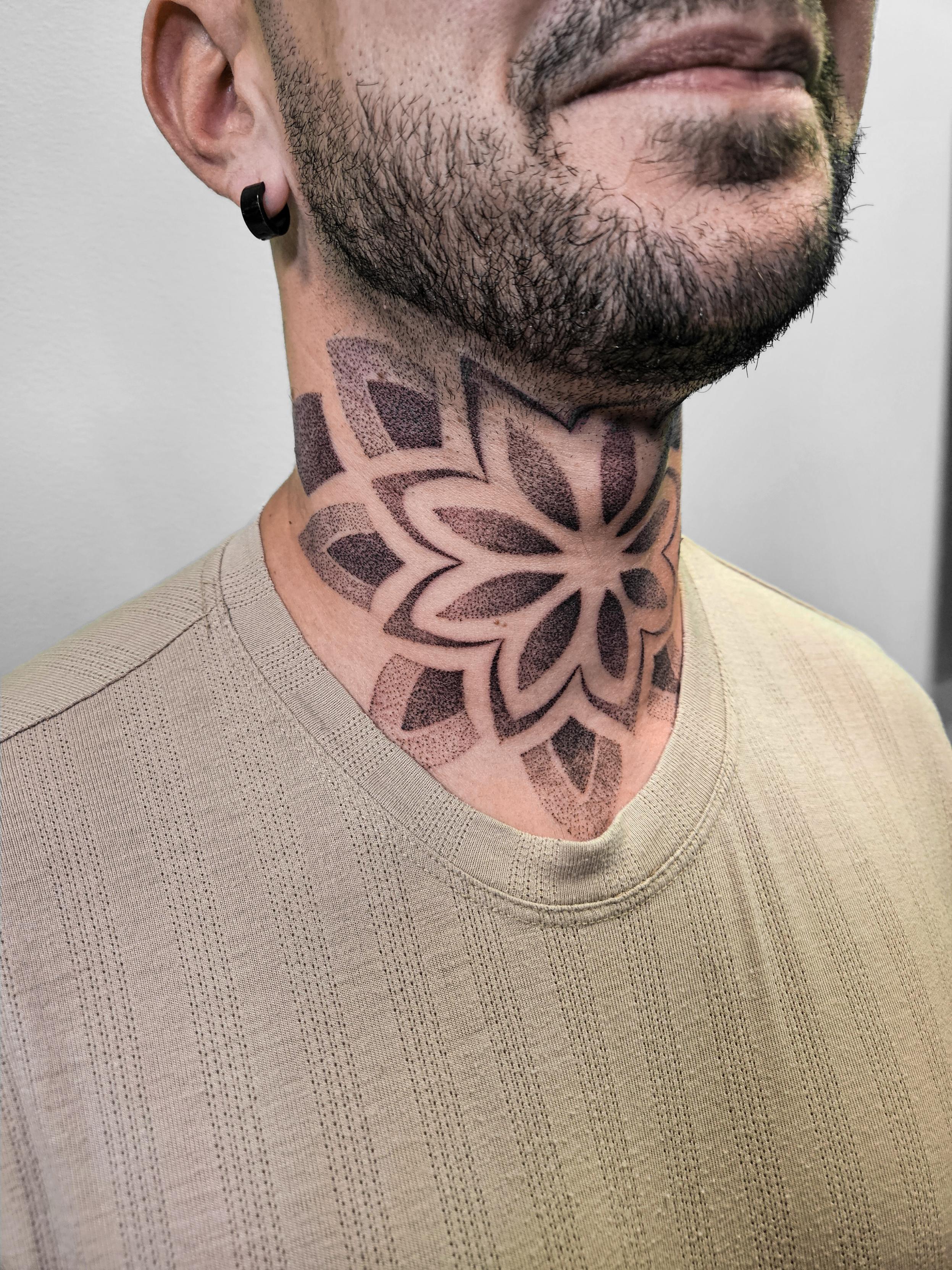 Ce tatouage présente un motif floral géométrique stylisé réalisé entièrement en technique dotwork sur le cou. Le design…