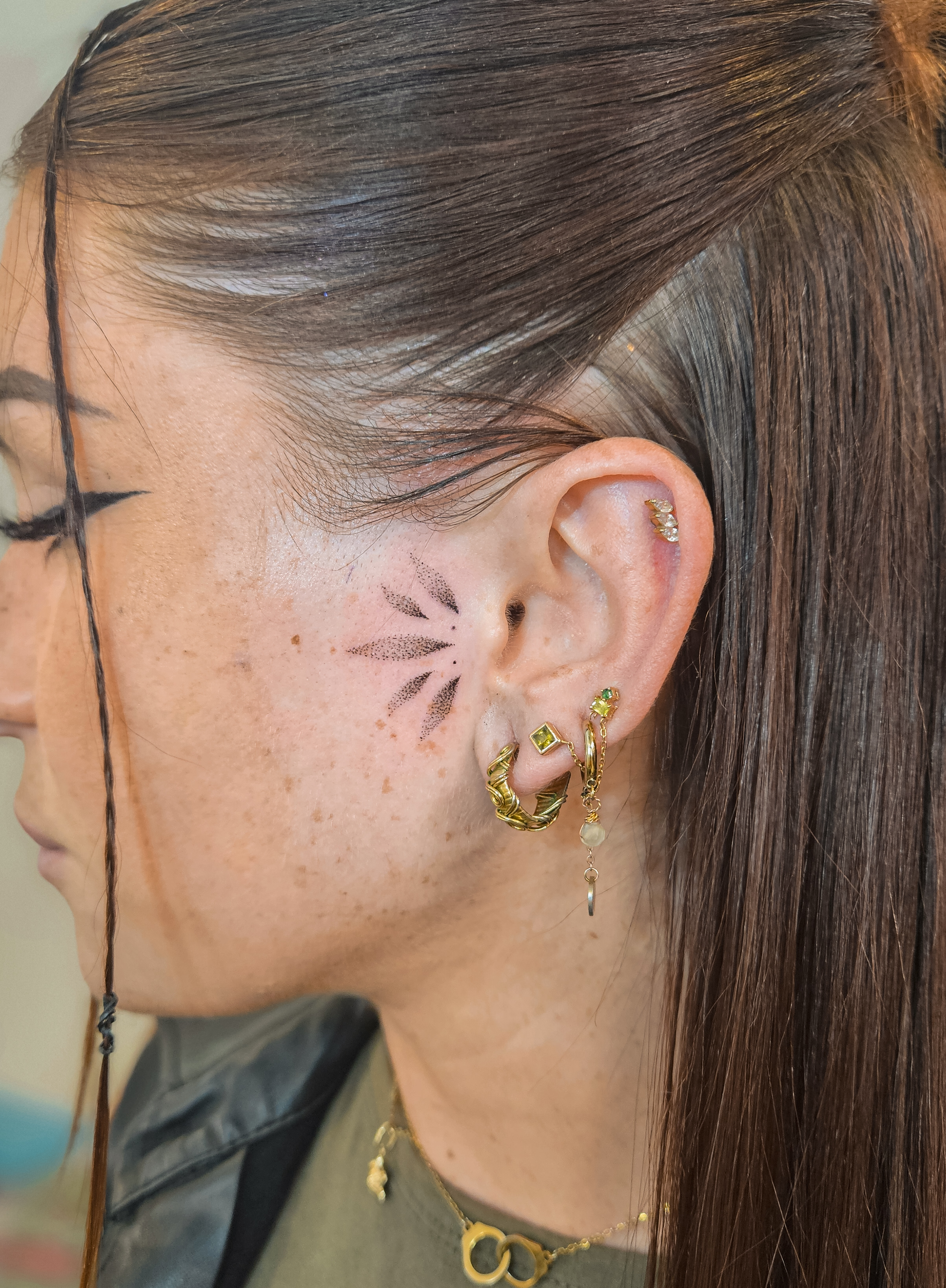 Ce tatouage présente un motif floral délicat situé sur le côté du cou, juste derrière l'oreille. Réalisé dans un style…