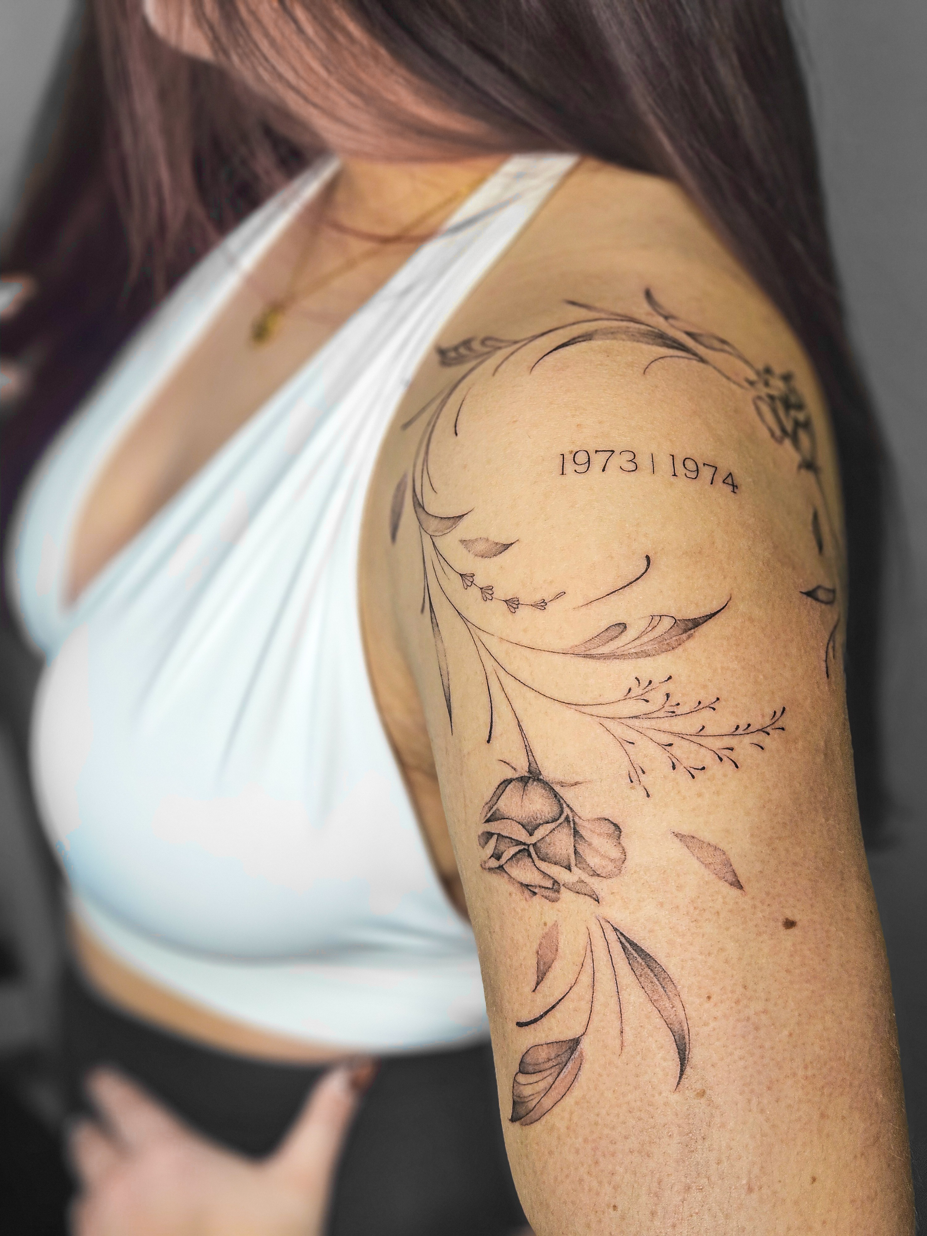Ce tatouage présente un style fine-line délicat sur le bras, composé d'éléments floraux et organiques entrelacés. Le design…