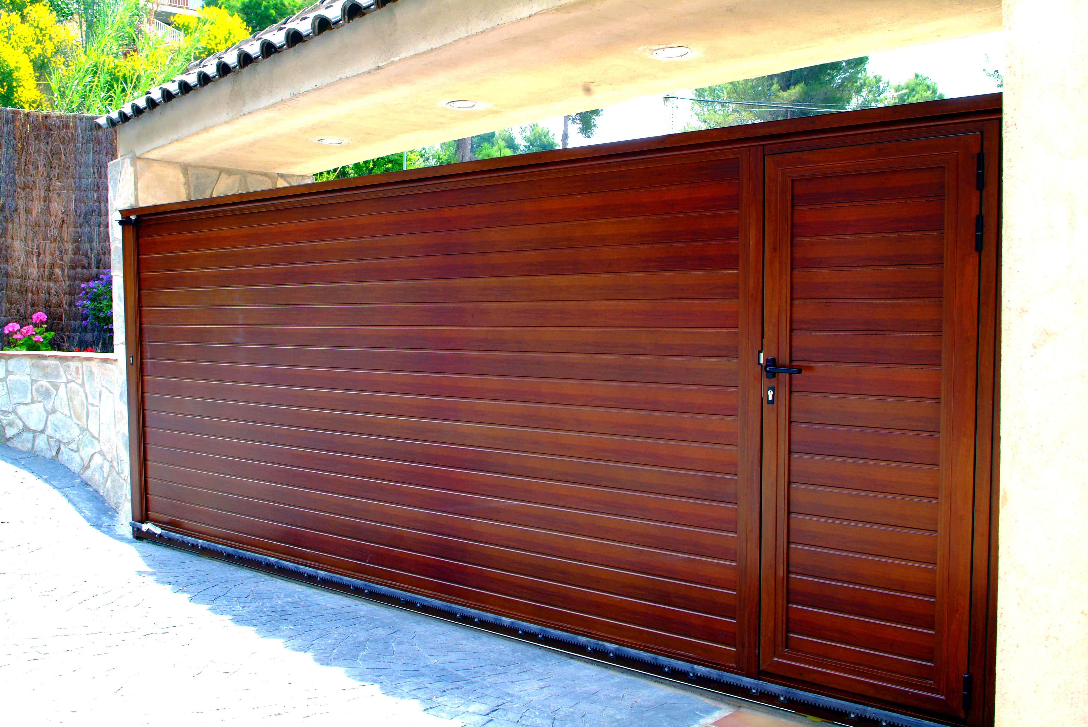 Puerta corredera de aluminio imitación madera con puerta peatonal incorporada